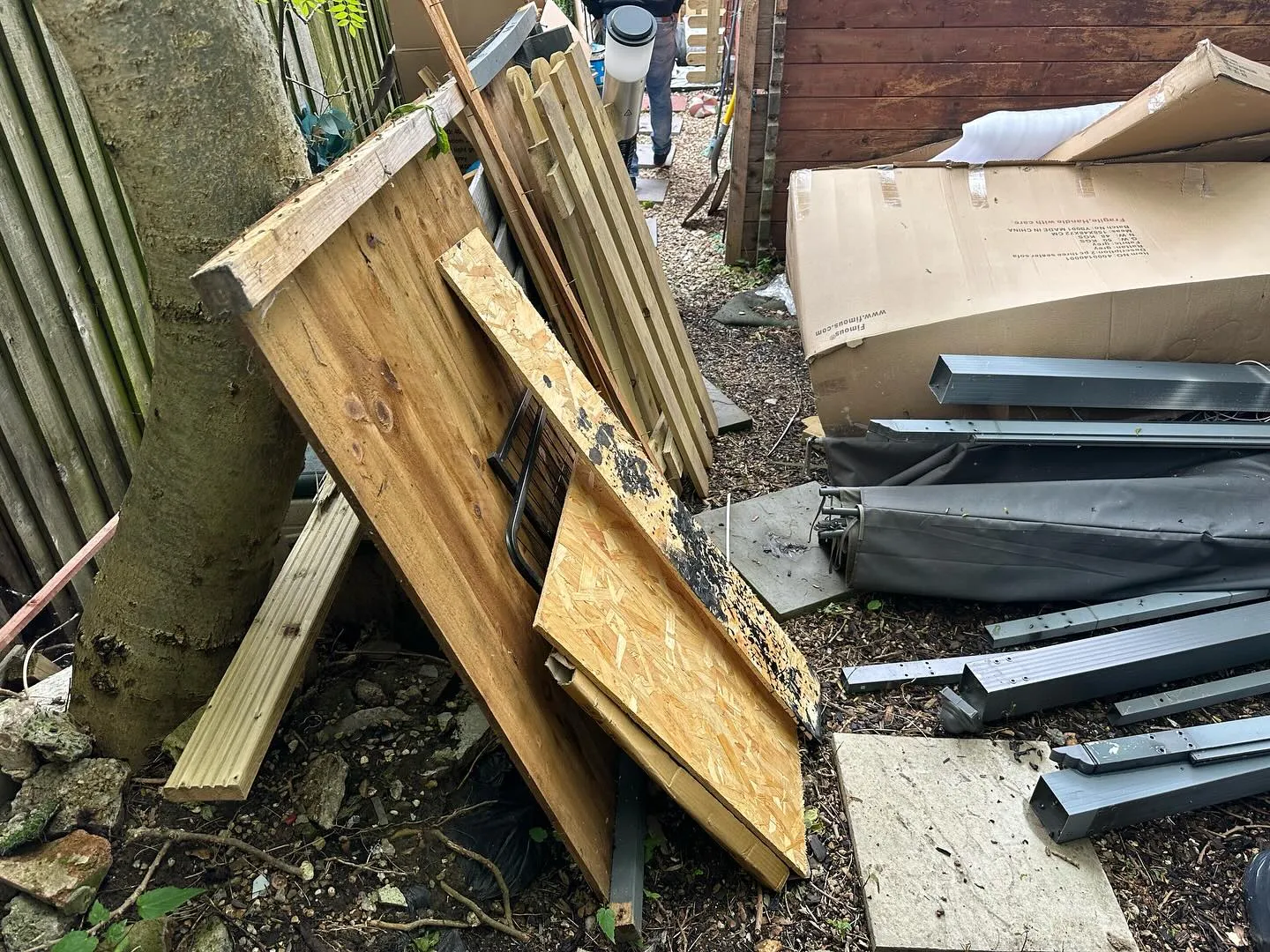 A pile of wood sitting next to a fence.
