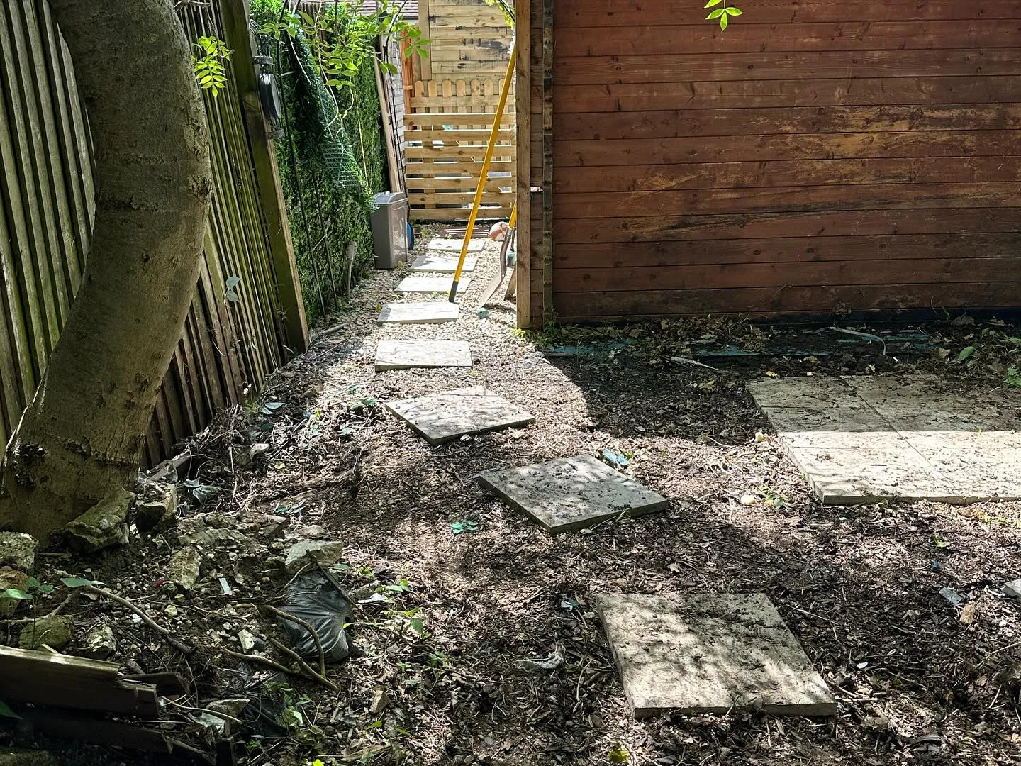 A backyard area with a wooden fence and a stone path.