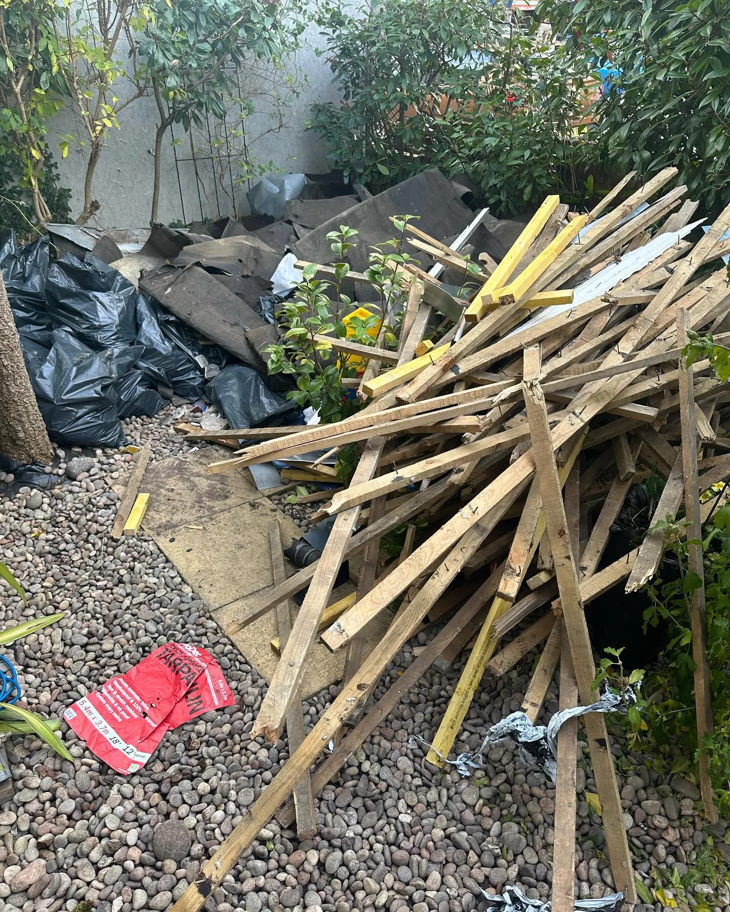 A pile of wood sticks sitting on top of a gravel covered ground.