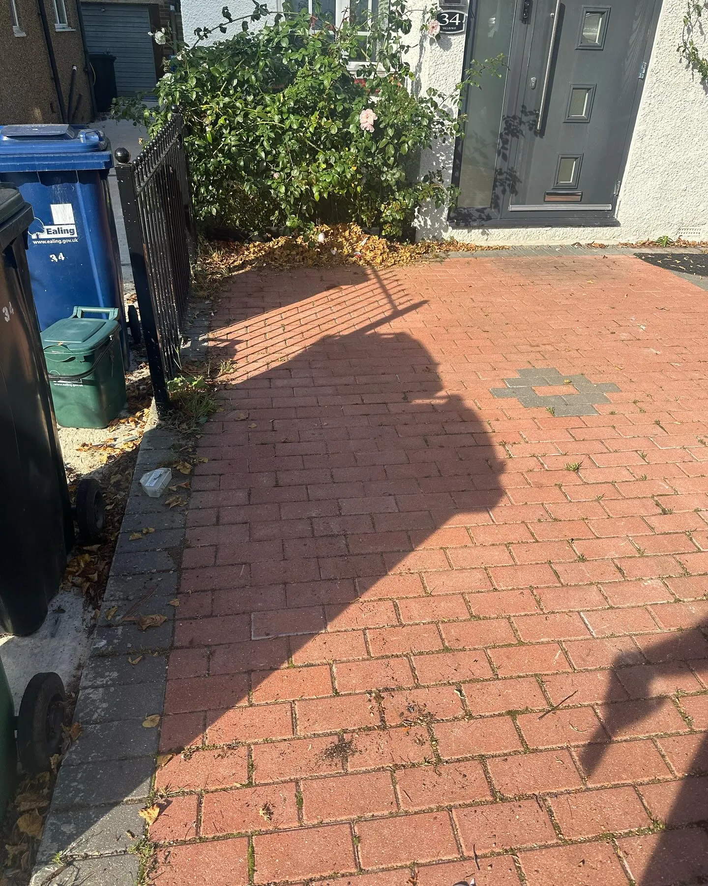 A red brick sidewalk next to a blue trash can.